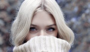blonďatá dívka ve svetru schovává rty